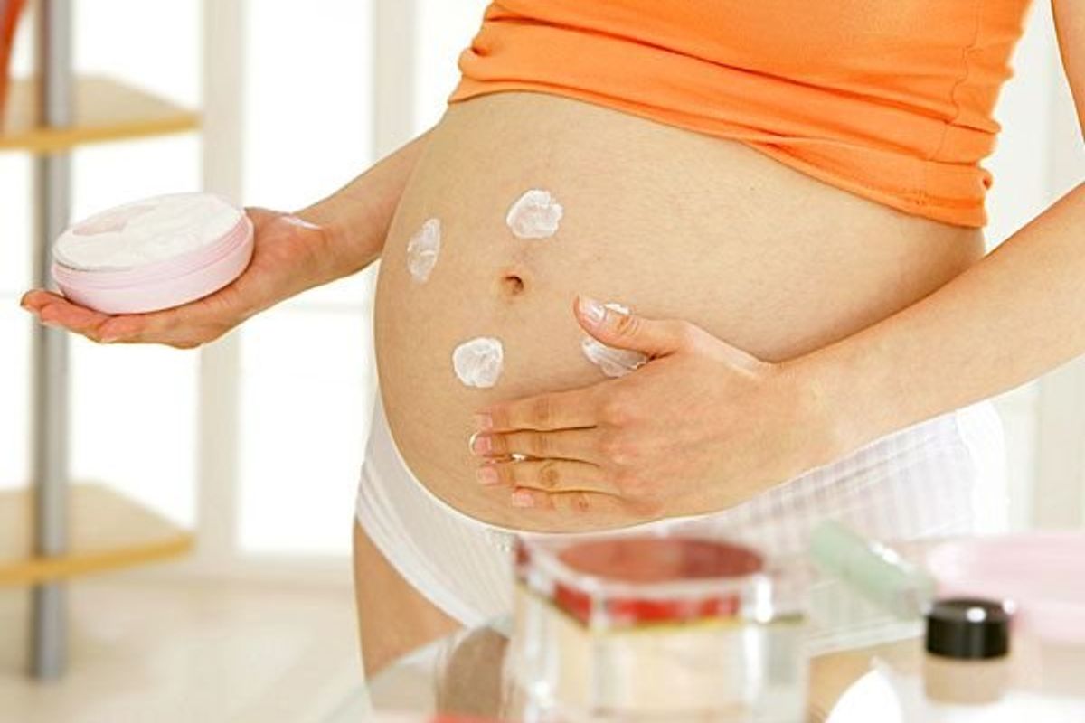 pregnant woman rubbing cream on her stomach