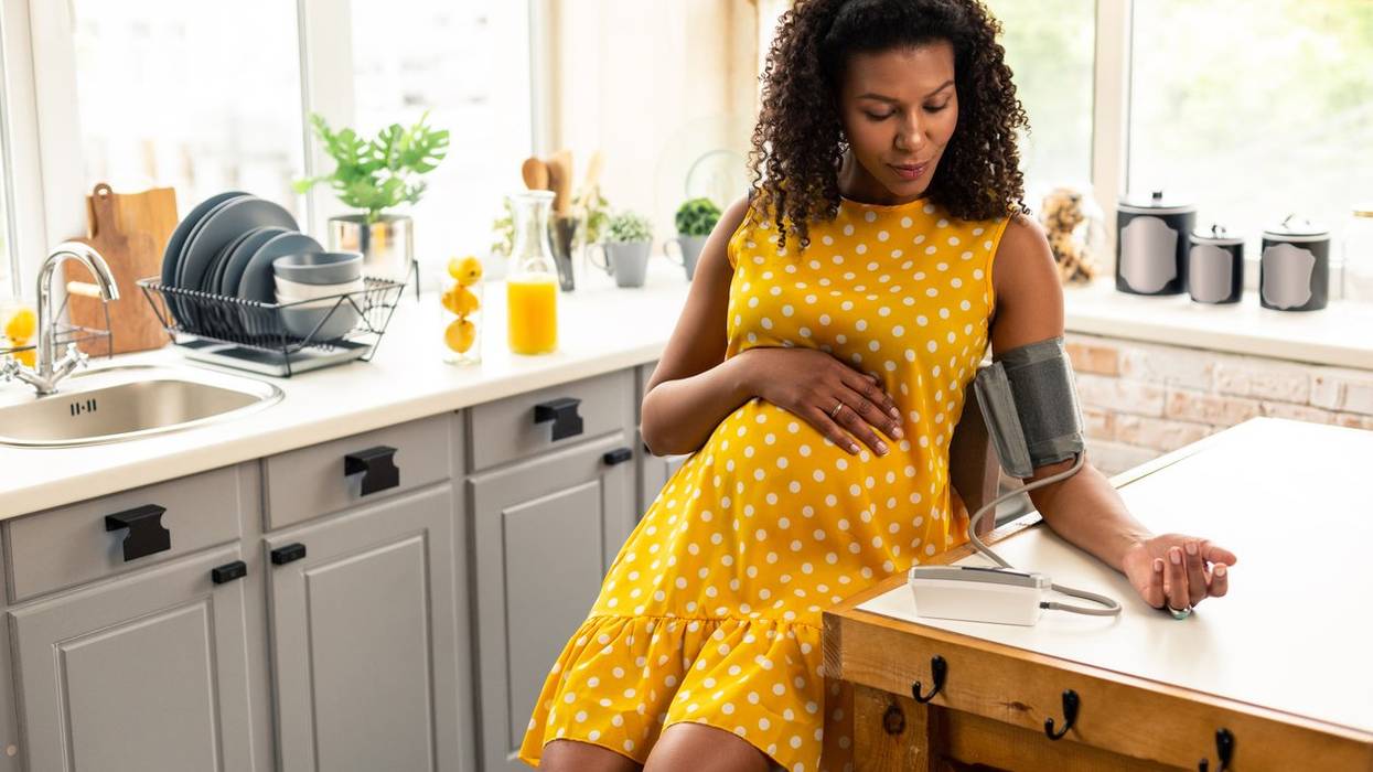 pregnant woman sitting in her kitchen during blood pressure measurement