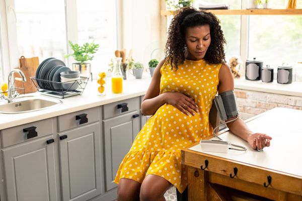 pregnant woman sitting in her kitchen during blood pressure measurement