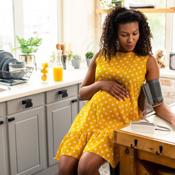 pregnant woman sitting in her kitchen during blood pressure measurement