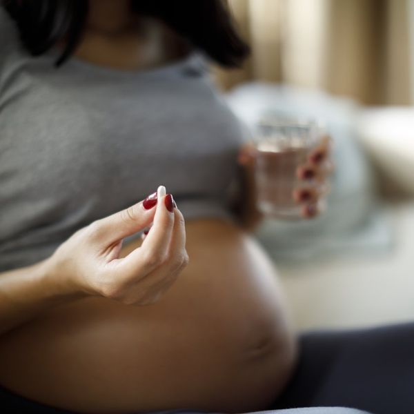 Pregnant woman taking pill at home