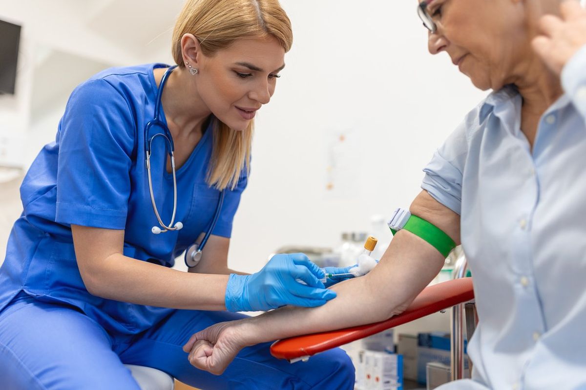 Preparation for blood test with senior woman by female doctor medical uniform on the table in white bright room