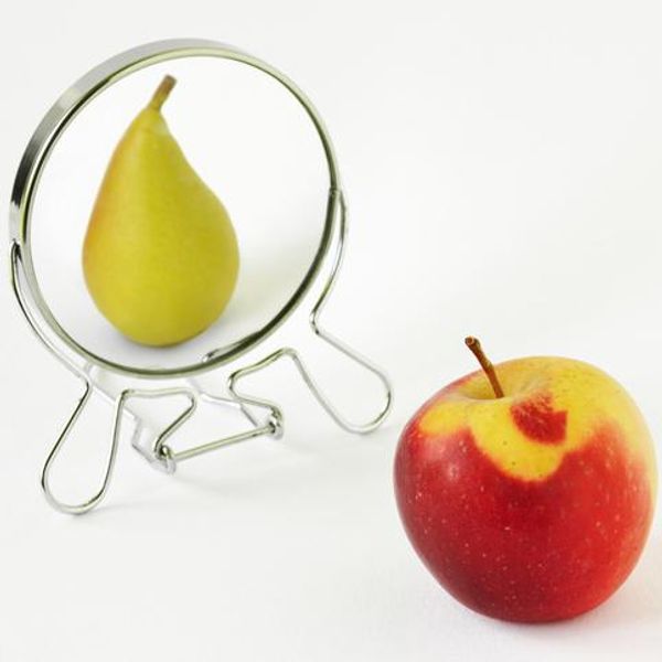Red apple looking in the mirror and seeing itself as a pear