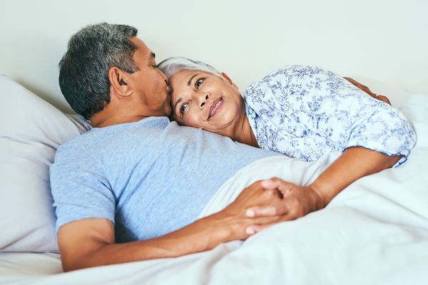 relaxed mature couple lying in bed together at home in during the morning hours