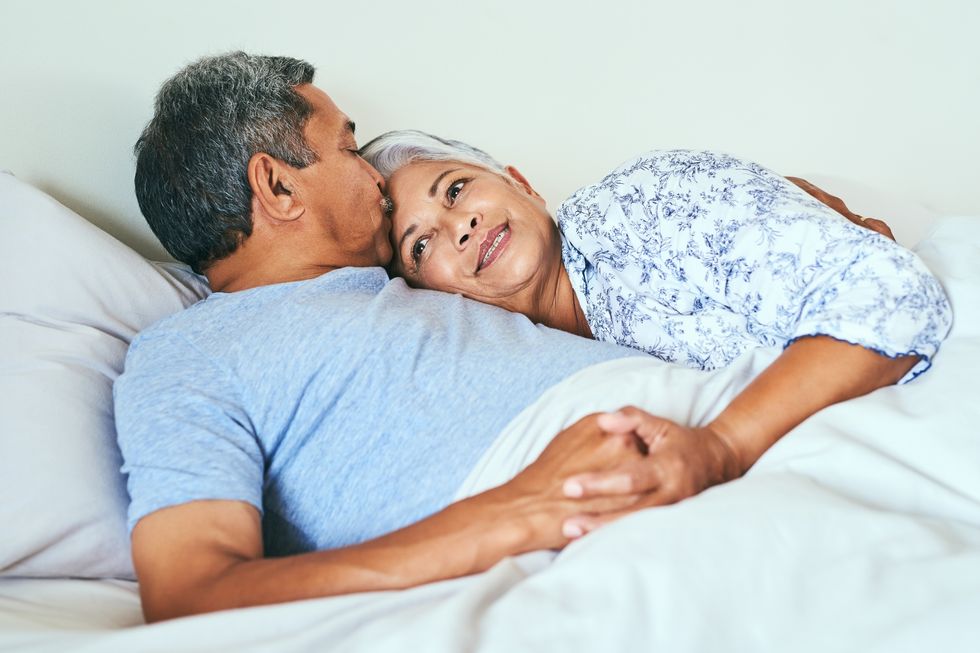 relaxed mature couple lying in bed together at home in during the morning hours