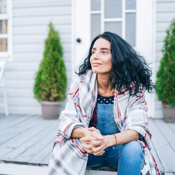 Sad mid adult woman sitting on stairs in front of her house