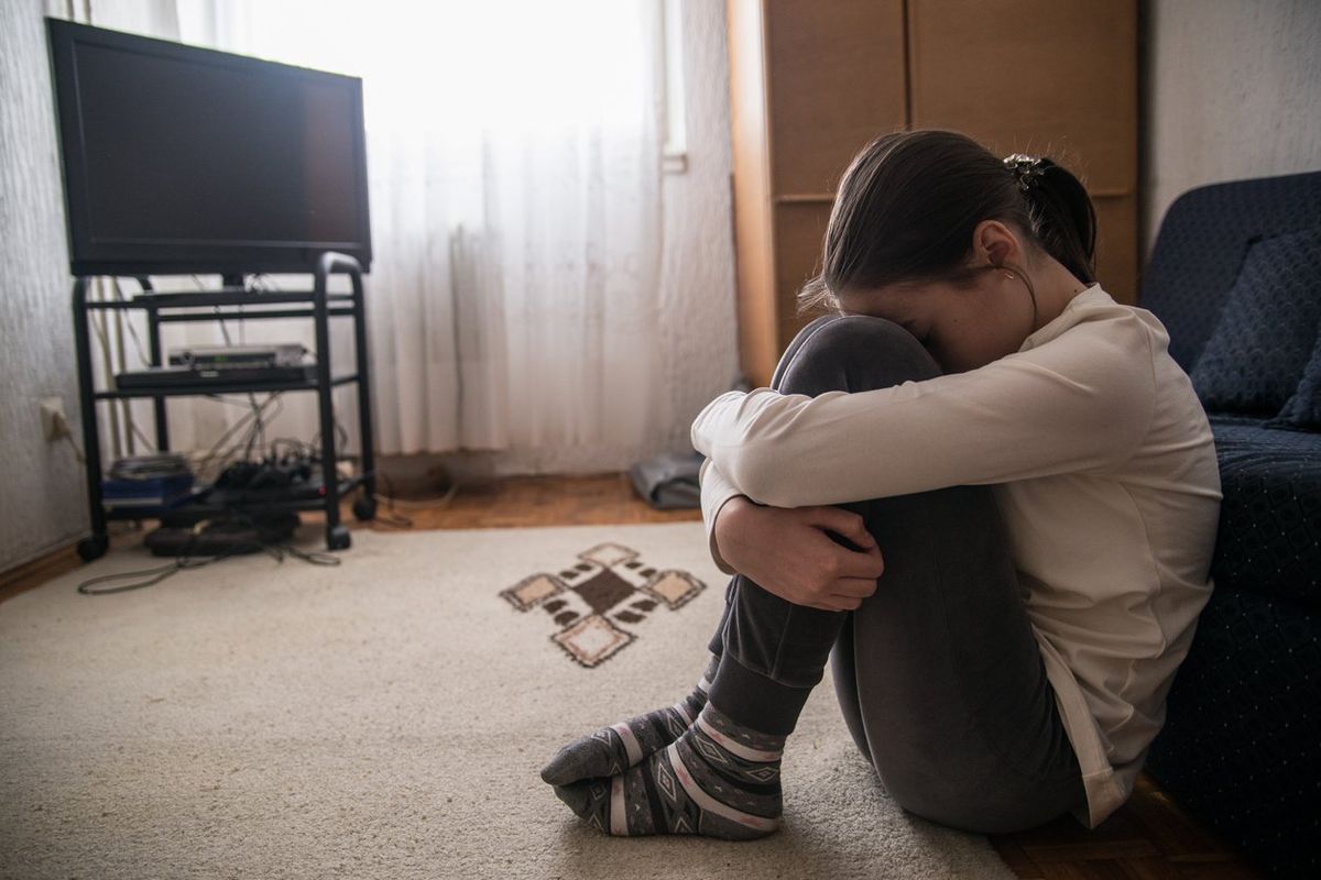 sad Teen woman holding her head in her living room during the day