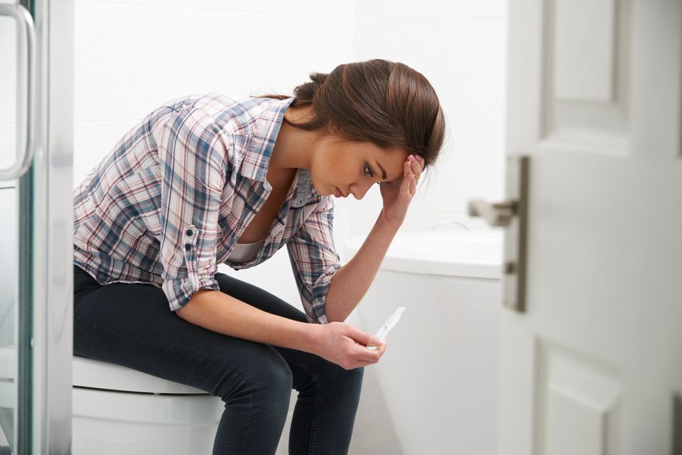 sad woman Sitting In Bathroom With Pregnancy Test 