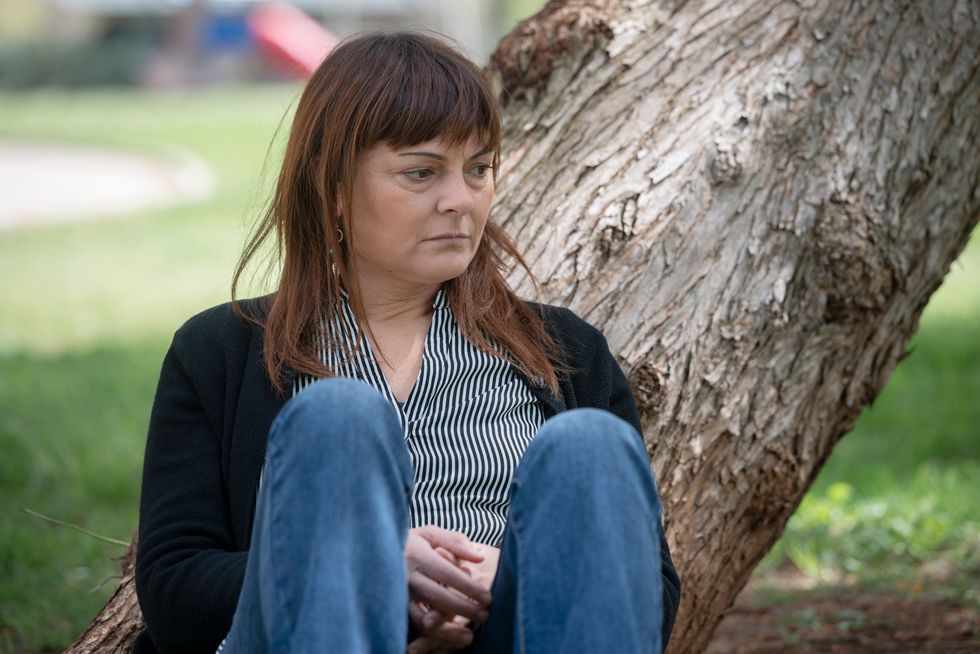sad woman sitting near a tree