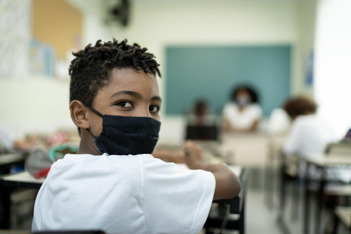 schoolboy wearing a mask, studying in the classroom