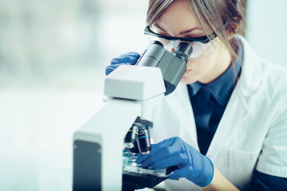 scientist looking through a microscope in a laboratory doing genetic testing for breast cancer