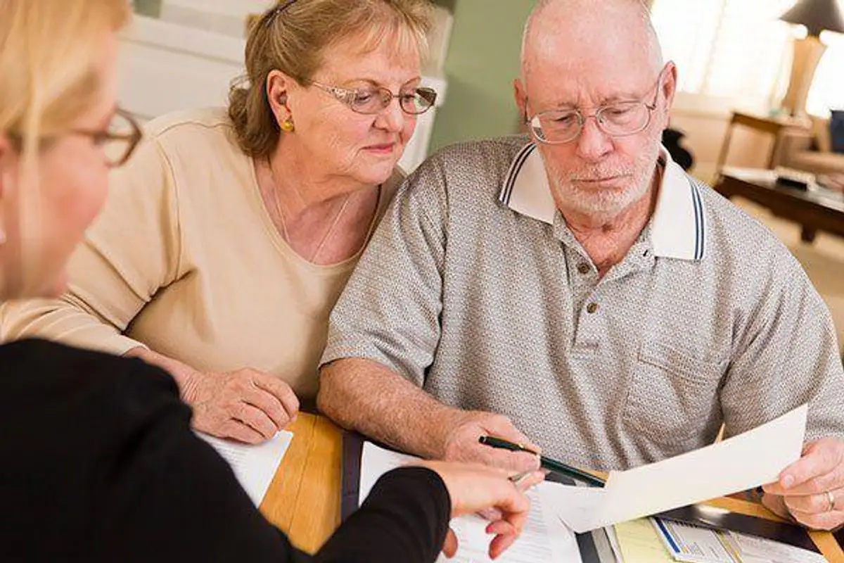 Senior Adult Couple Going Over Papers in Their Home with Agent.