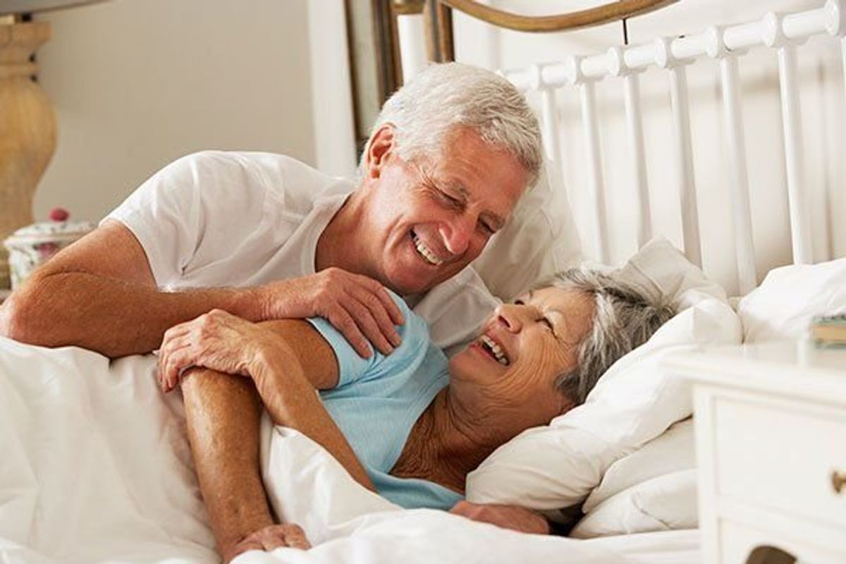 Senior Couple In Bed Together Smiling And Laughing.