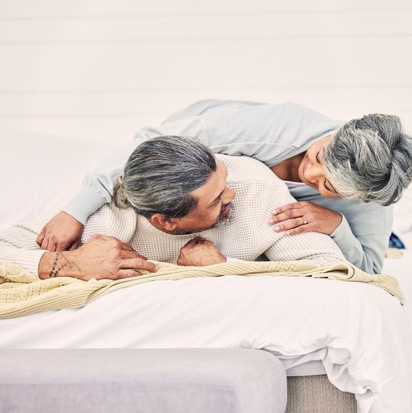 Senior couple, laugh and play on bed in home, hotel and happy together with romance