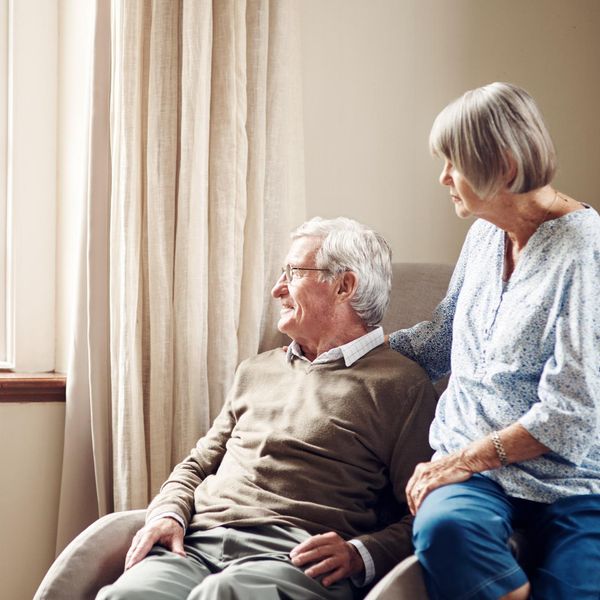 senior couple looking thoughtfully out of a window at home