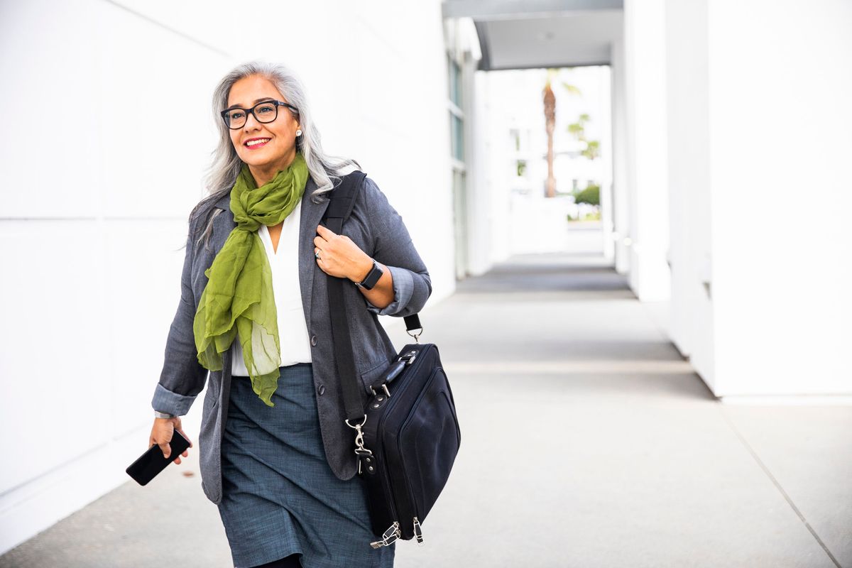 Senior hispanic businesswoman Walking down hallway