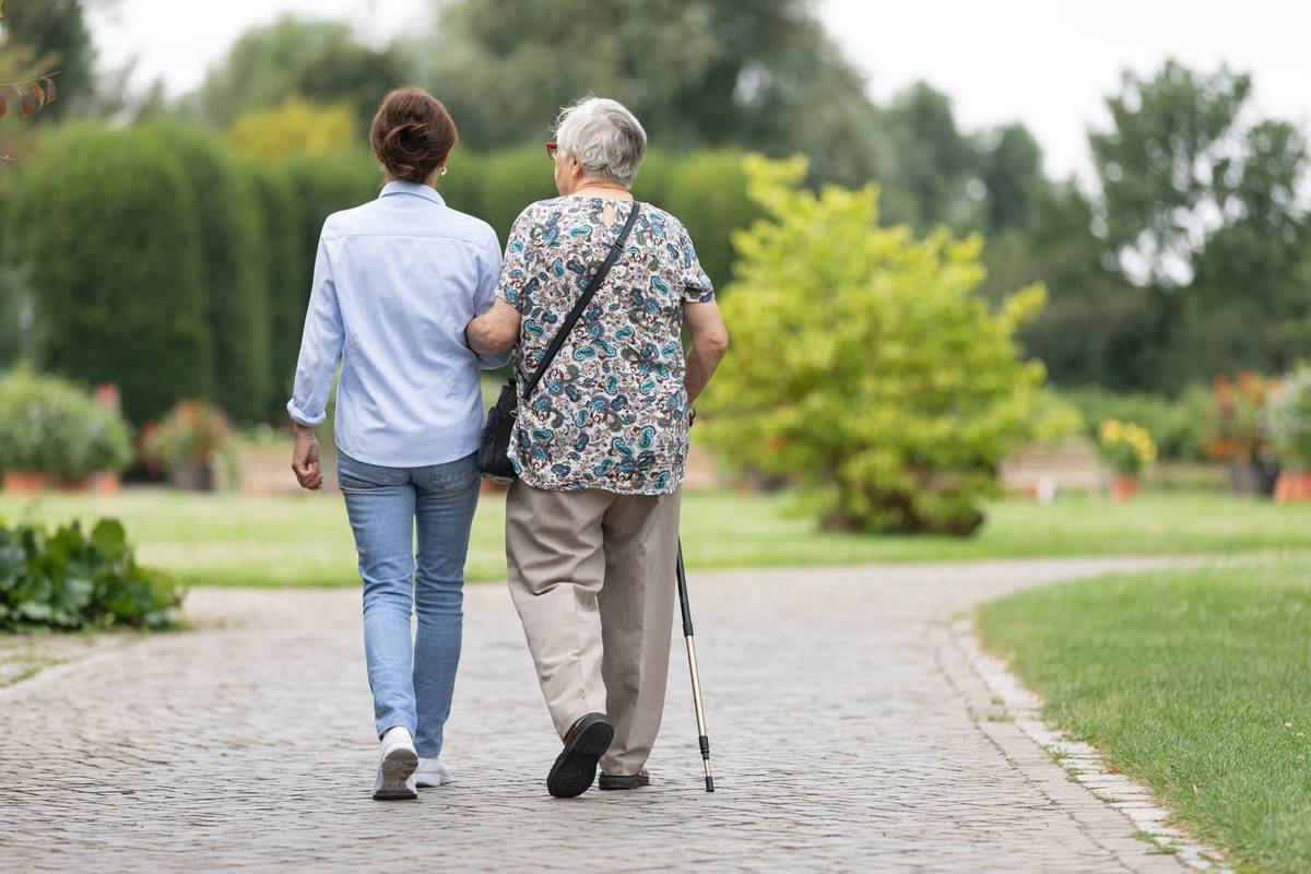 senior woman and caregiver walking outdoors