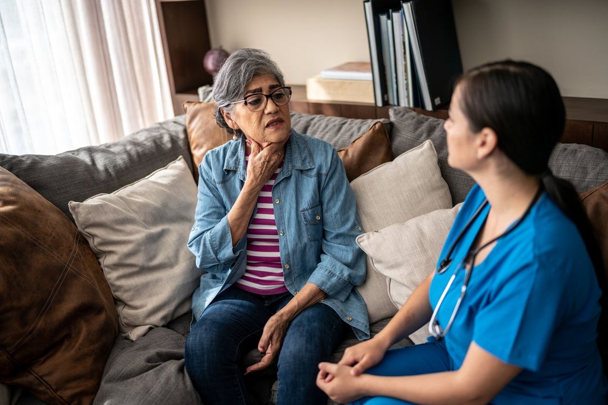 Senior woman explaining her pain to nurse at nursing home