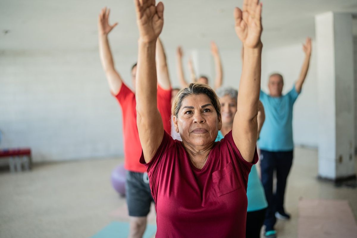 Senior woman stretching with classmates at the yoga studio