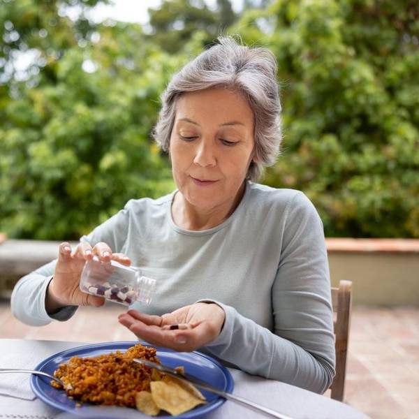 Senior woman taking her medicines with food while eating lunch