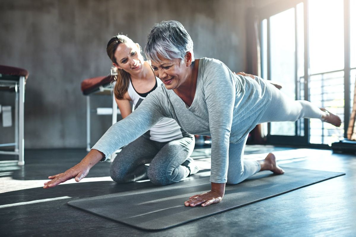 senior woman working out with her physiotherapist due to multiple sclerosis