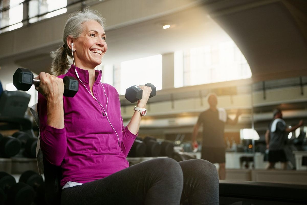 senior woman working out with weights at the gym