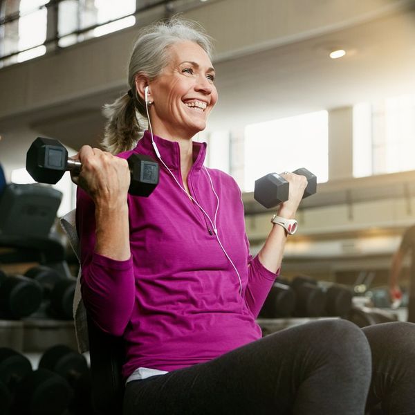 senior woman working out with weights at the gym