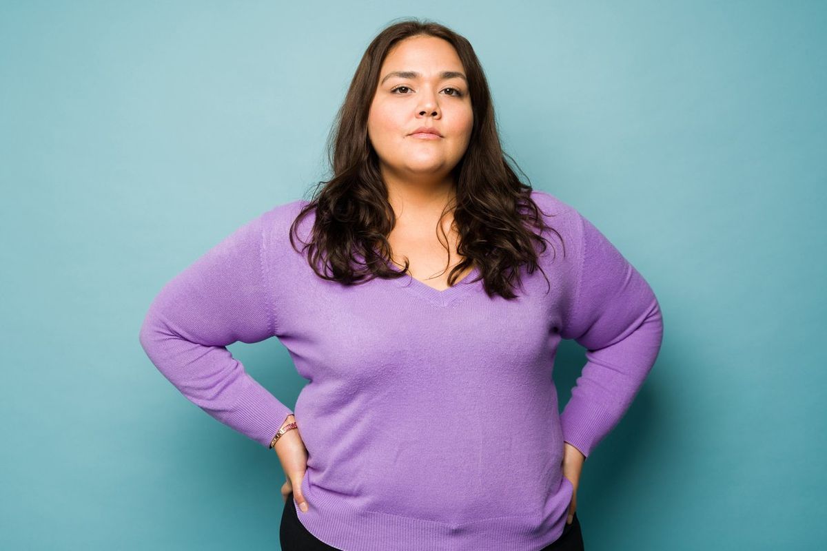 Serious overweight hispanic woman with her hands on the hips looking determined
