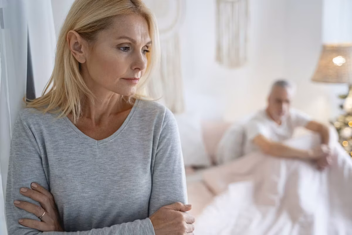 Serious worried woman standing with crossed arms after quarreling with man