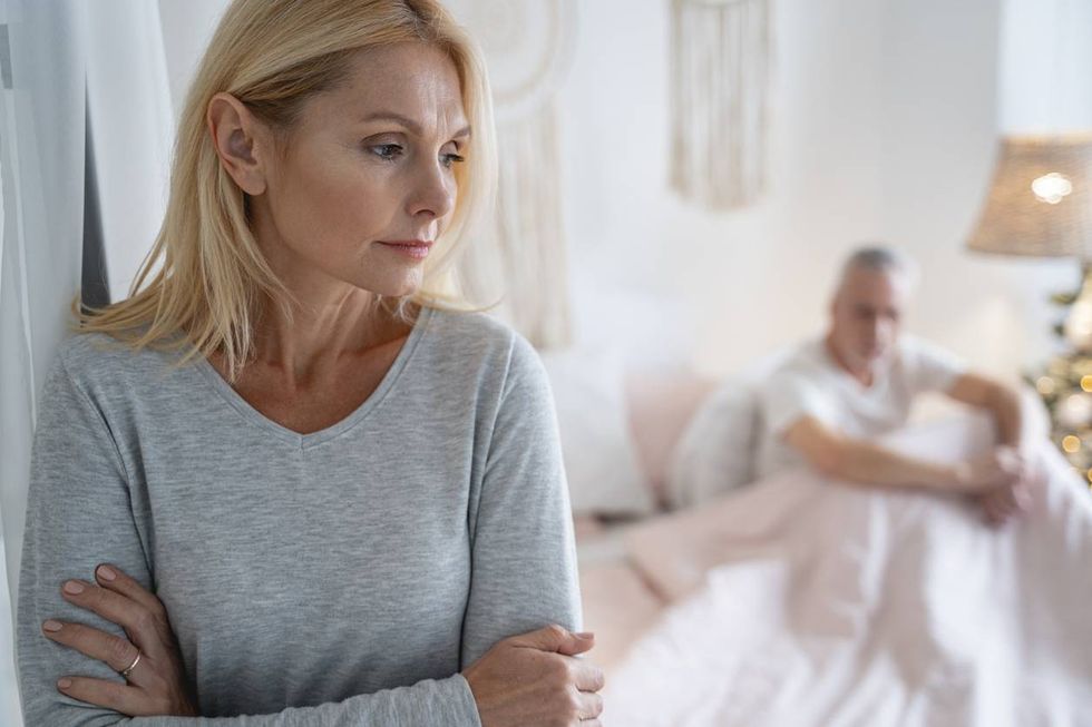 serious worried woman standing with crossed arms after quarreling with man