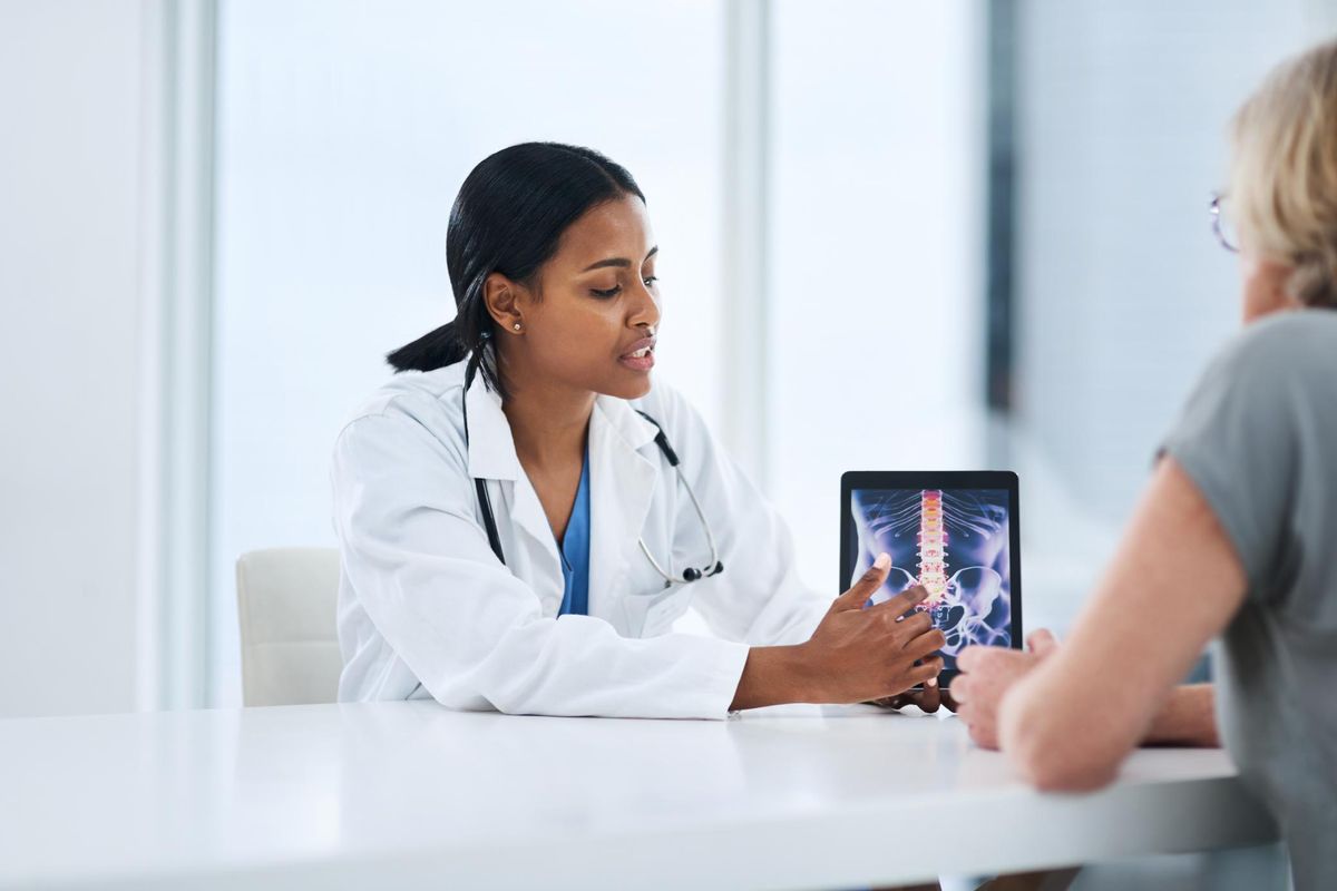 Shot of a young doctor using a digital tablet during a consultation with a senior woman