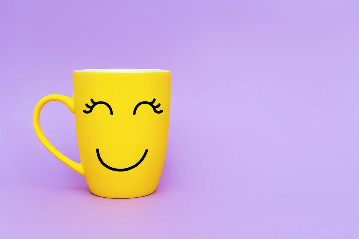 Smiley yellow coffee cup on purple background