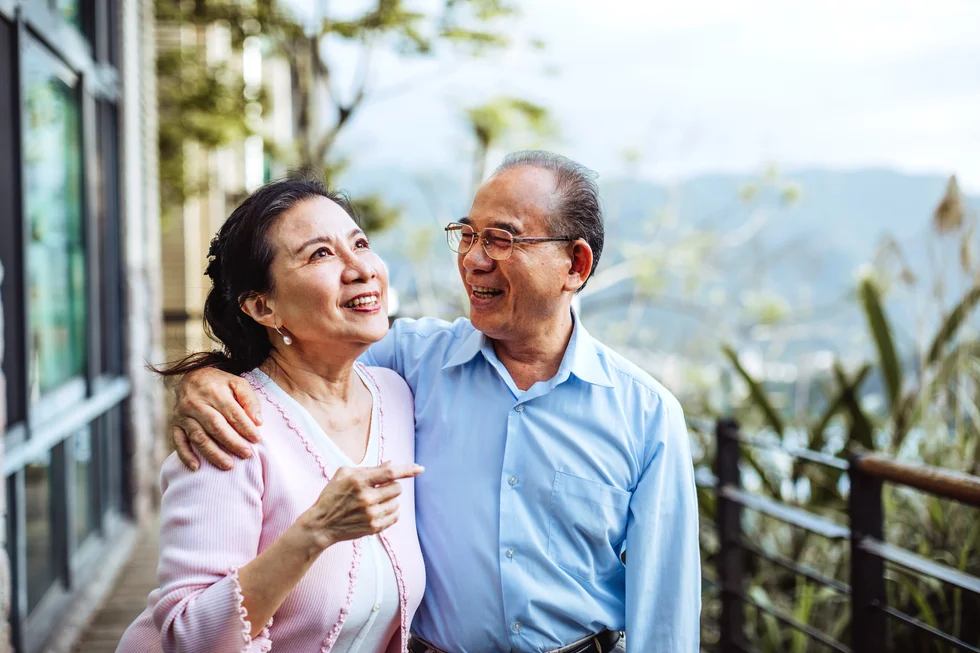 Smiling senior Taiwanese couple hugging in backyard
