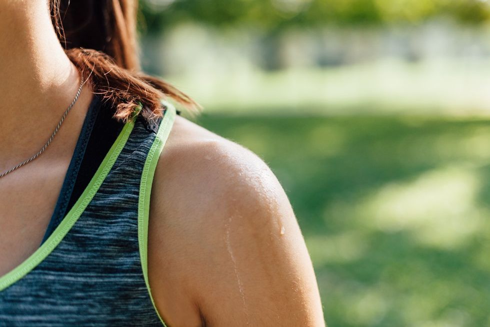 Sportswoman shoulder in sunlight after workout.