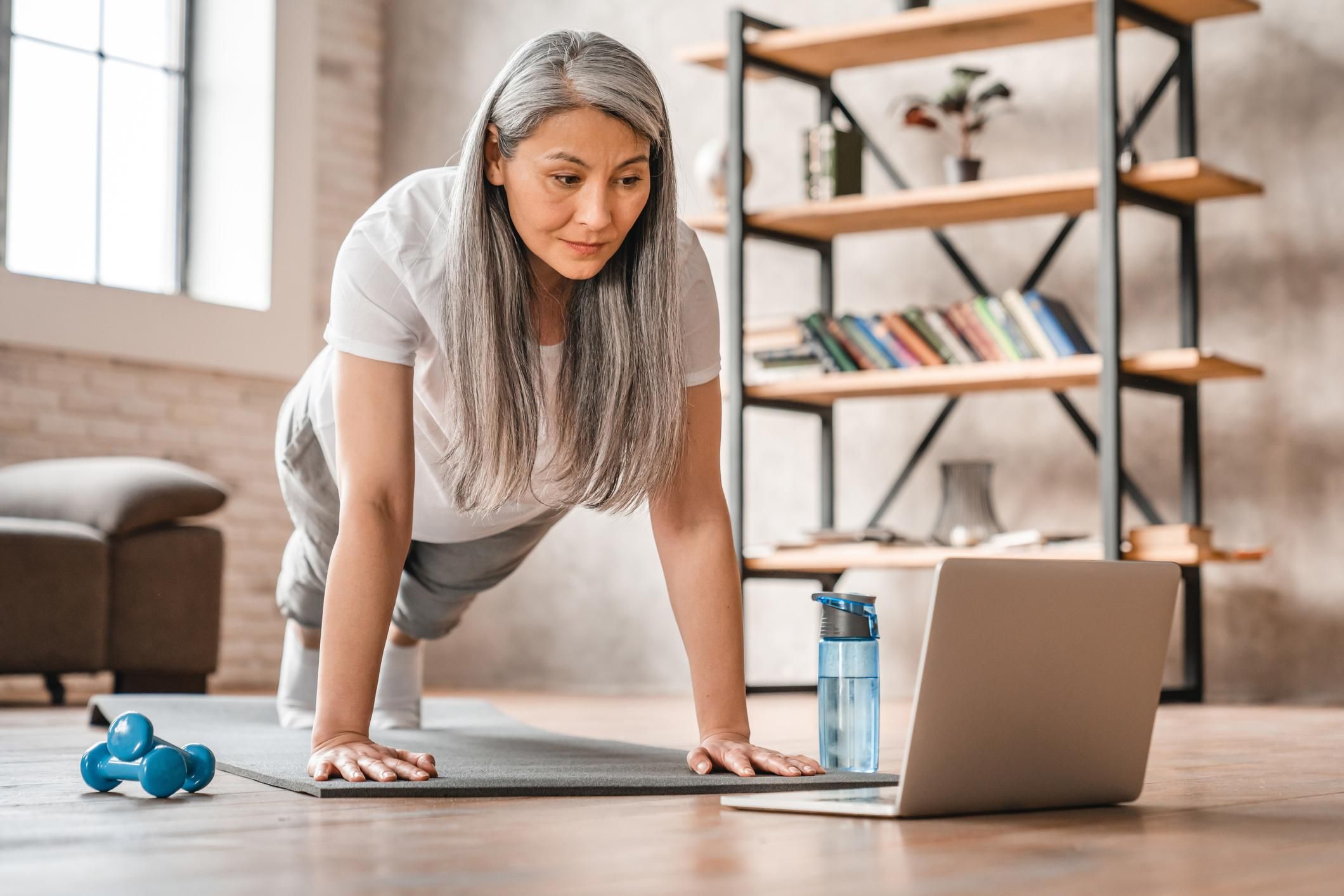 Sporty middle-aged woman standing in plank position