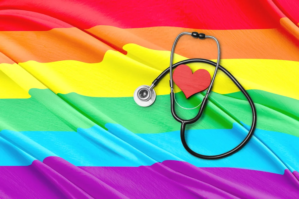 Stethoscope and heart shape with rainbow flag background