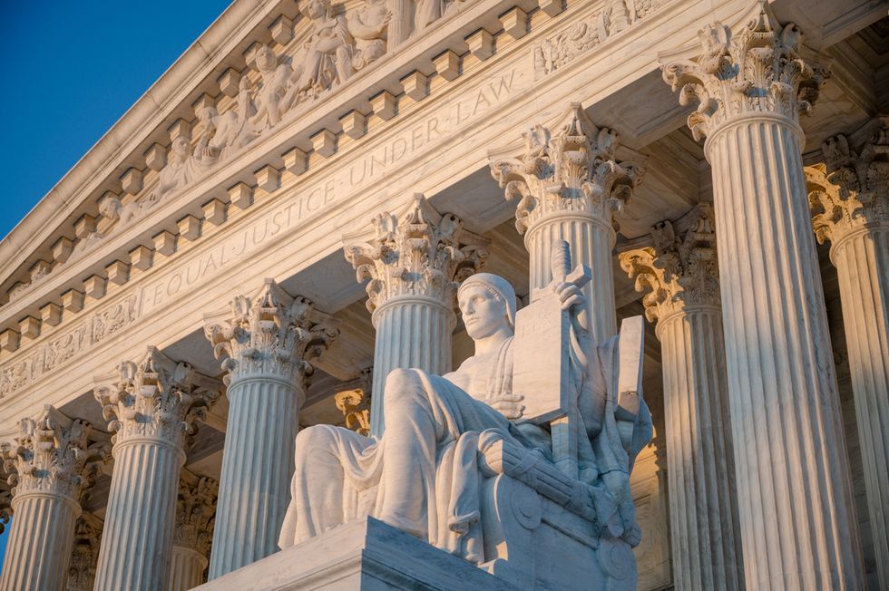 Sunset glow illuminated statue and colonnade of US Supreme court in Washington DC