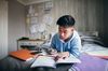Teenage boy lying on his bed while concentrating on homework for his exams.