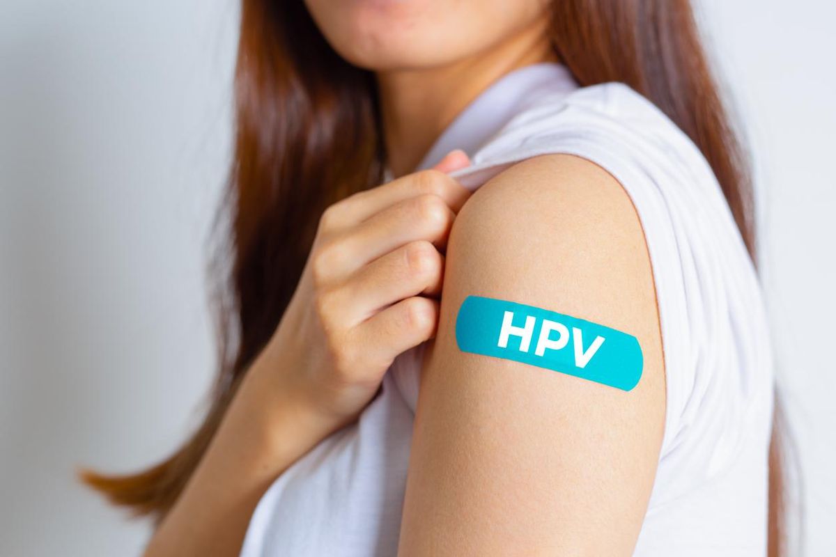 Teenager woman showing off an blue bandage after receiving the HPV vaccine