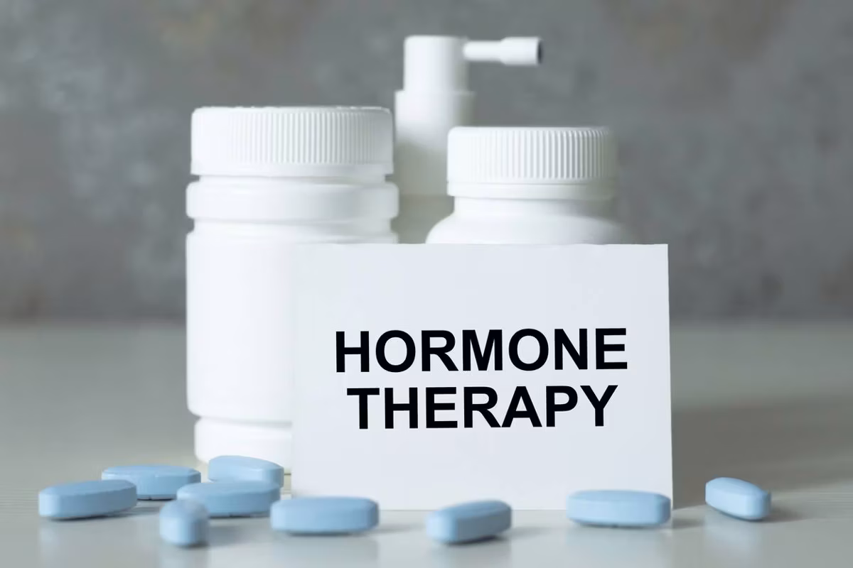 text hormone THERAPY on a white card next to medicine jars and scattered blue pills