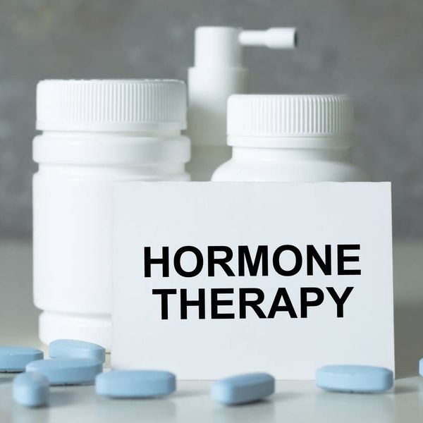 text hormone THERAPY on a white card next to medicine jars and scattered blue pills