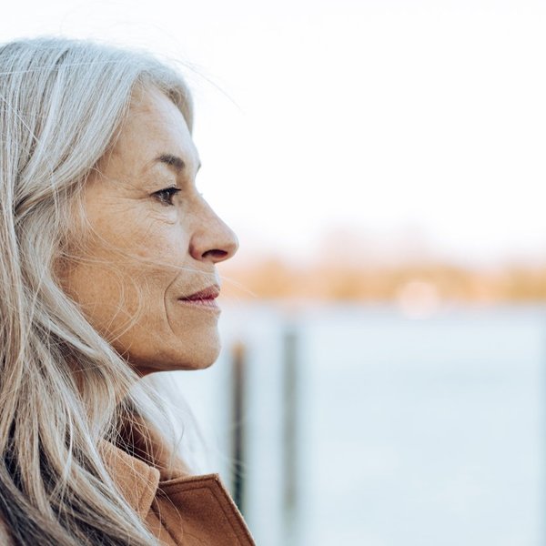 thoughtful mature woman standing on the beach and looking at the distance.