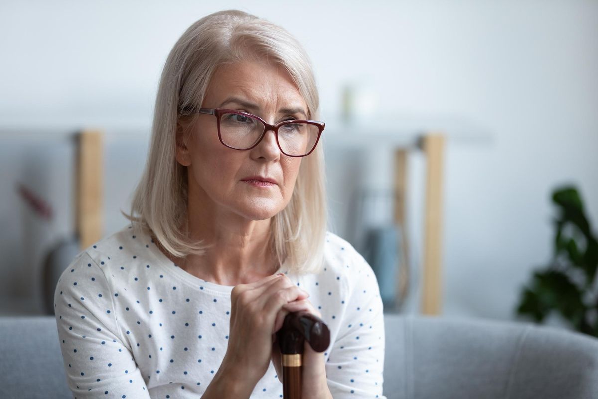 thoughtful old woman holding cane