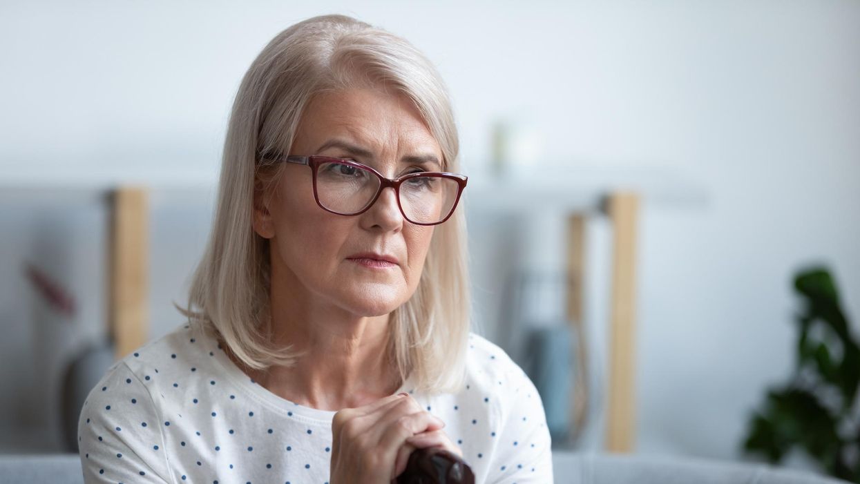 thoughtful old woman holding cane