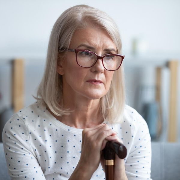 thoughtful old woman holding cane