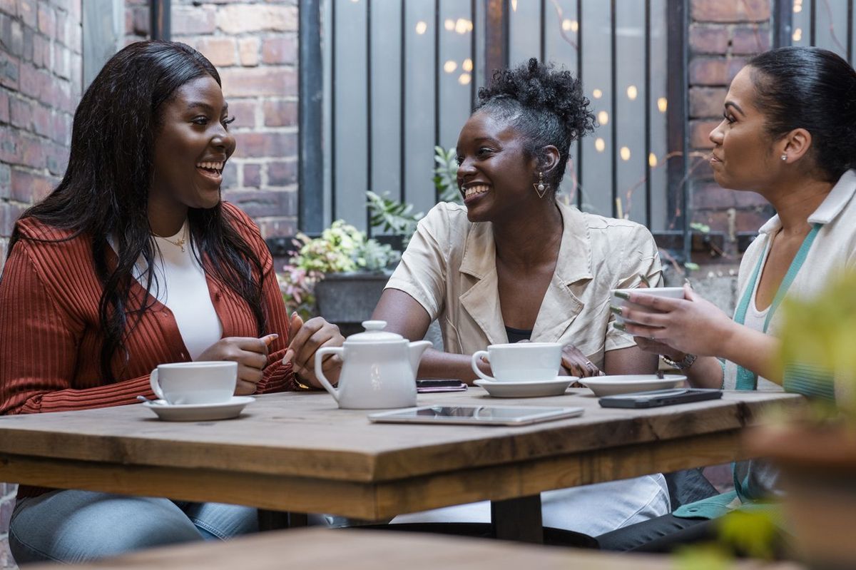 three female friends/co-workers having coffee/tea together on an outdoor terrace in the North East of England