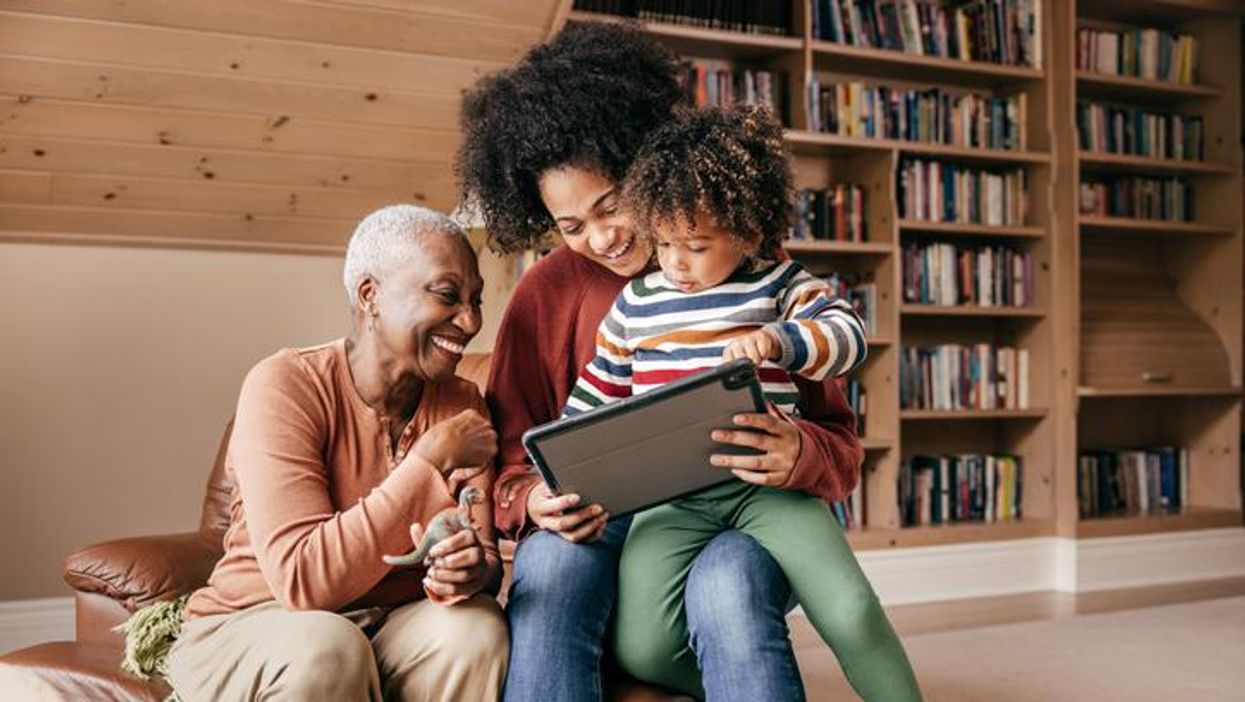 Three generation family sitting with tablet and laughing together
