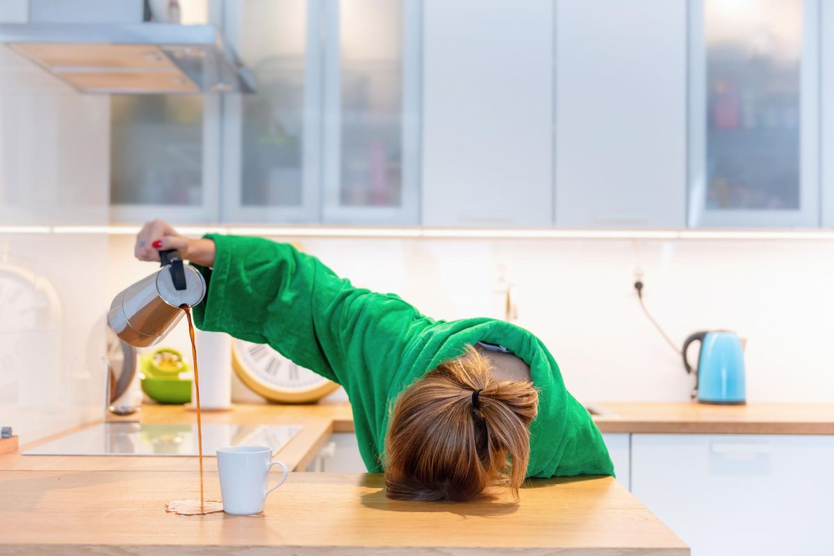 Tired woman sleeping on the table in the kitchen at breakfast. Trying to drink morning coffee stock photo
