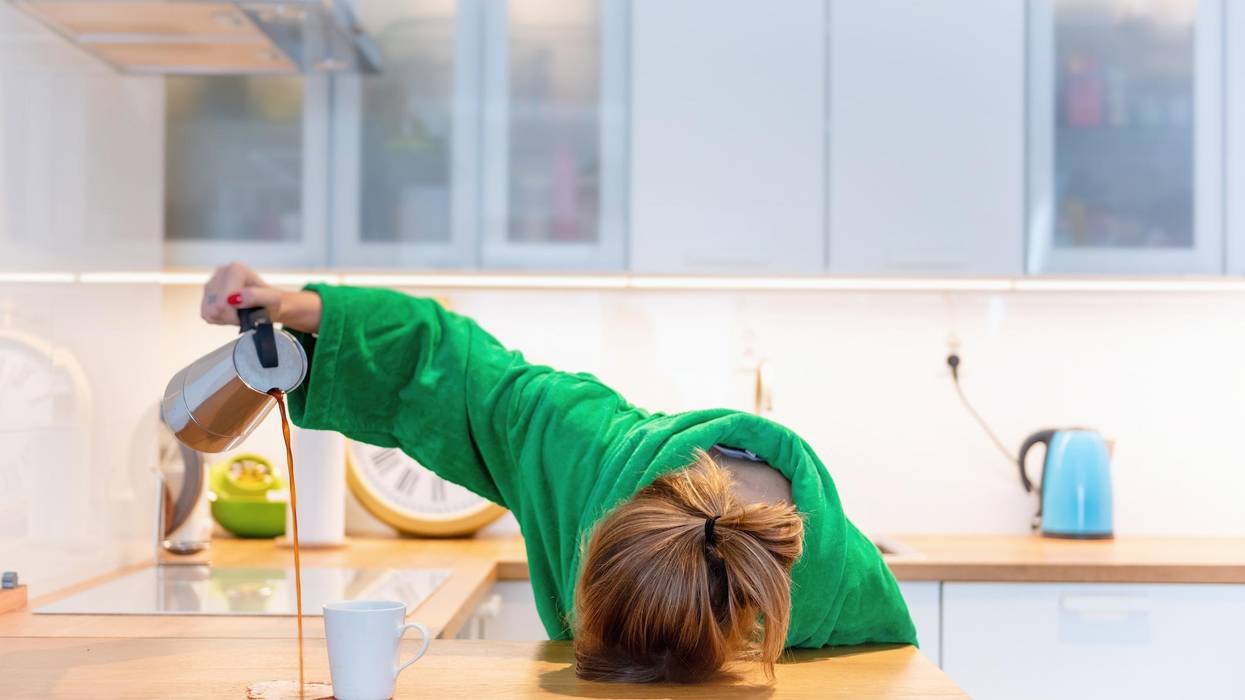 Tired woman sleeping on the table in the kitchen at breakfast. Trying to drink morning coffee stock photo
