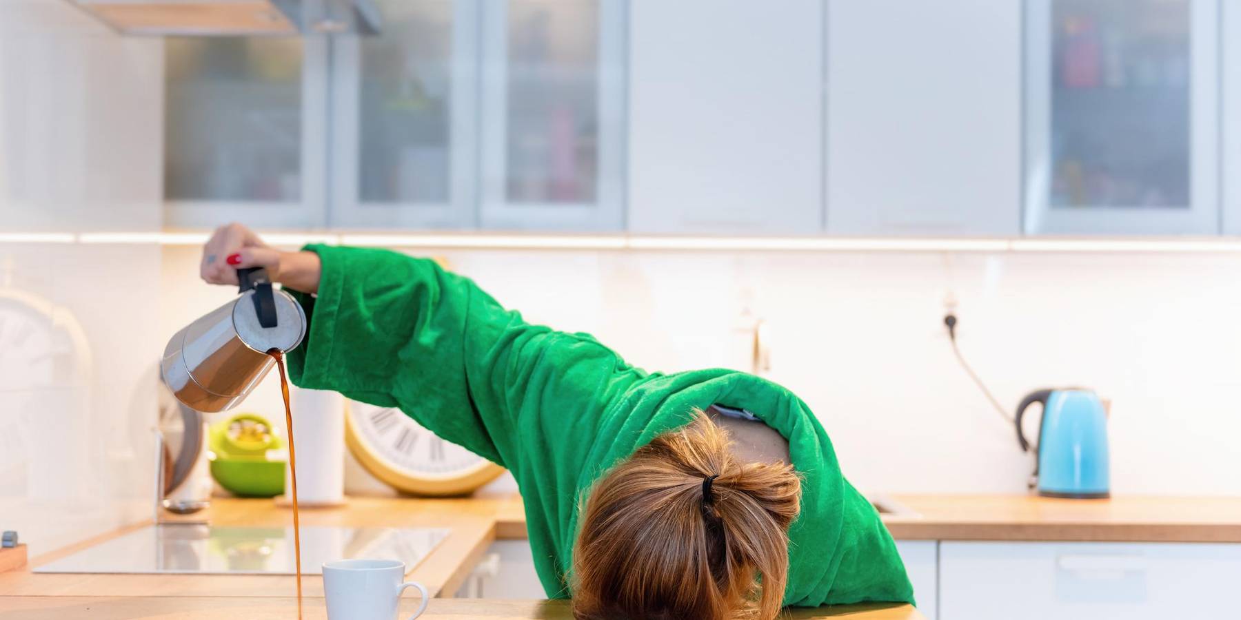 Tired woman sleeping on the table in the kitchen at breakfast. Trying to drink morning coffee stock photo